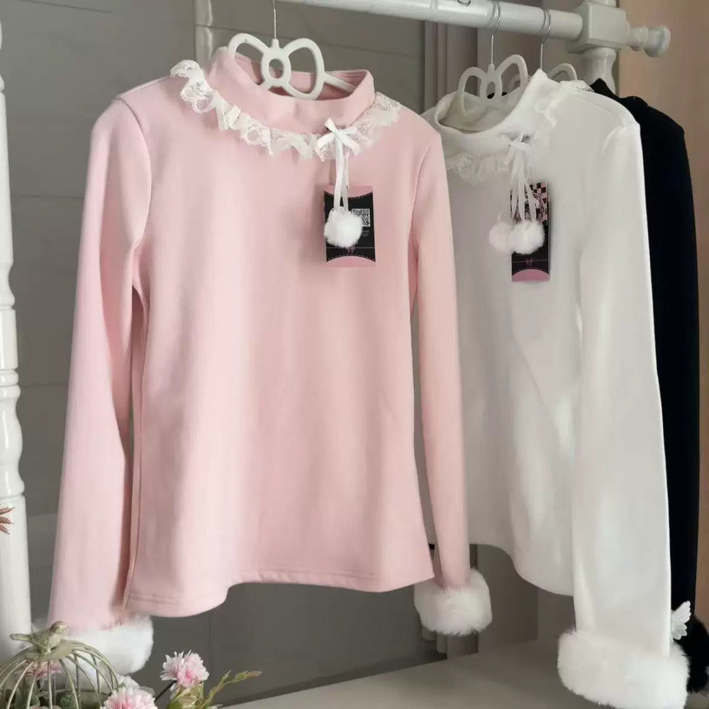White long-sleeve base layer top with a lace collar and furry cuffs displayed on a rack.