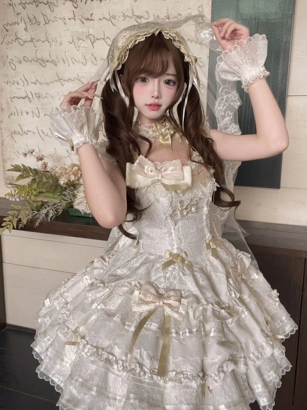 Apricot and ivory Lolita dress with lace tiers, gold bows, hand sleeves and a large train.