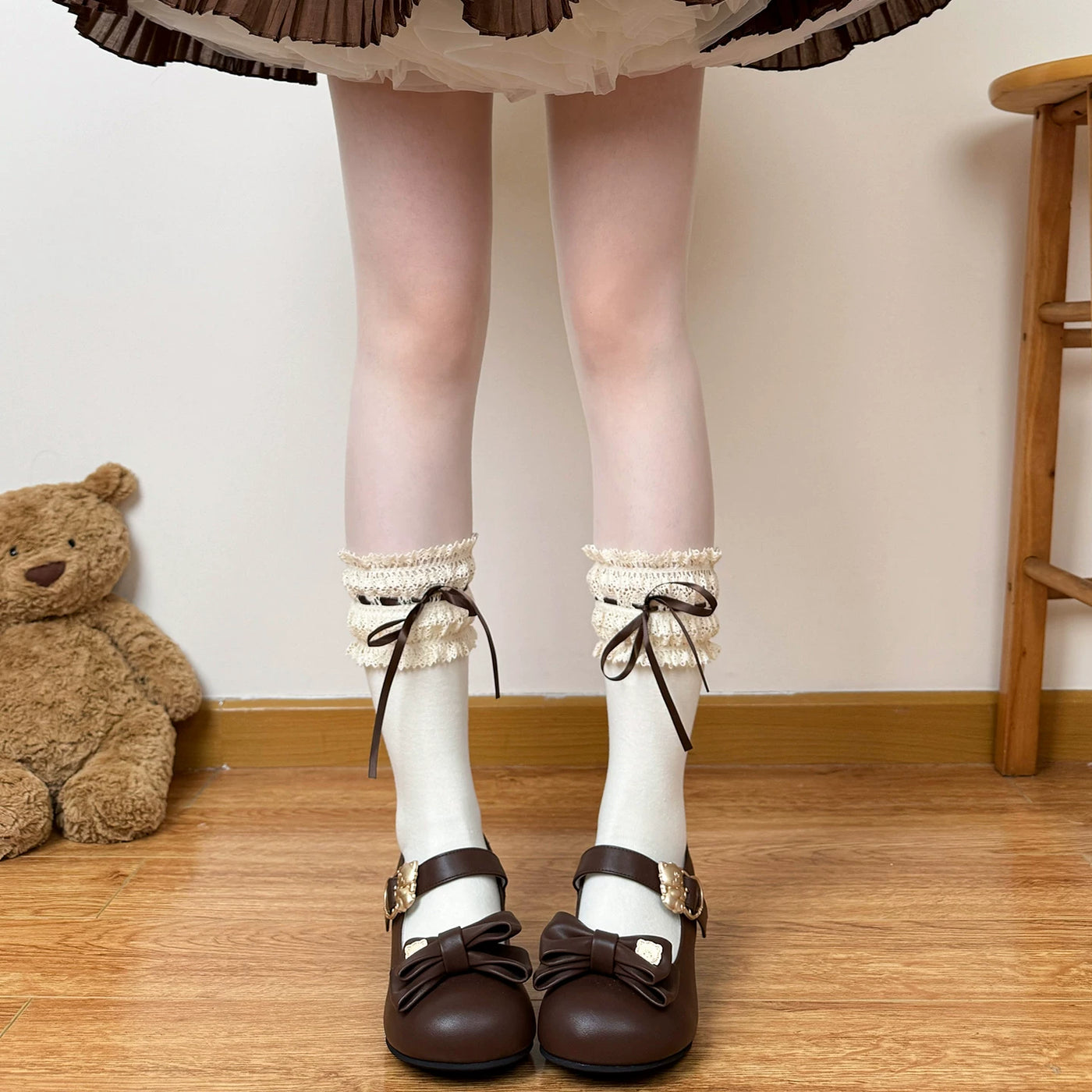Model wearing brown over-the-knee socks with cream lace cuffs and dark ribbon ties.