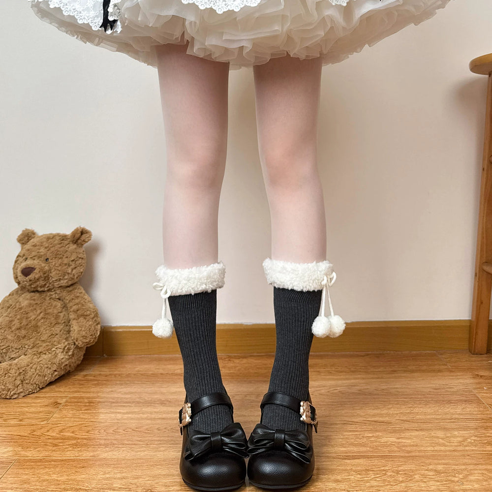 White scrunched mid-calf socks with fuzzy cuffs and dangling pom-poms