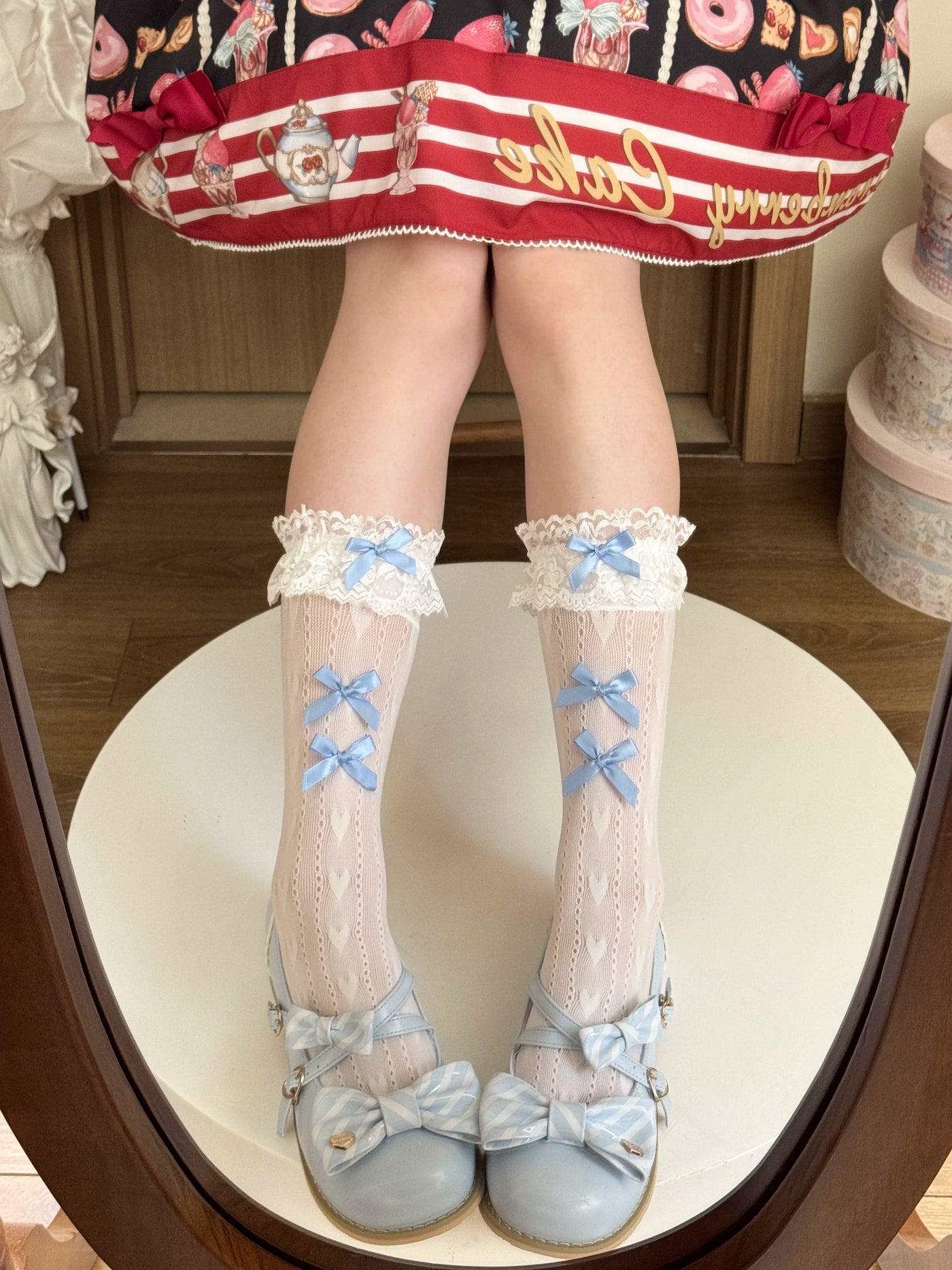 White lace-trimmed mid-calf socks with bows worn with white Mary Jane shoes.