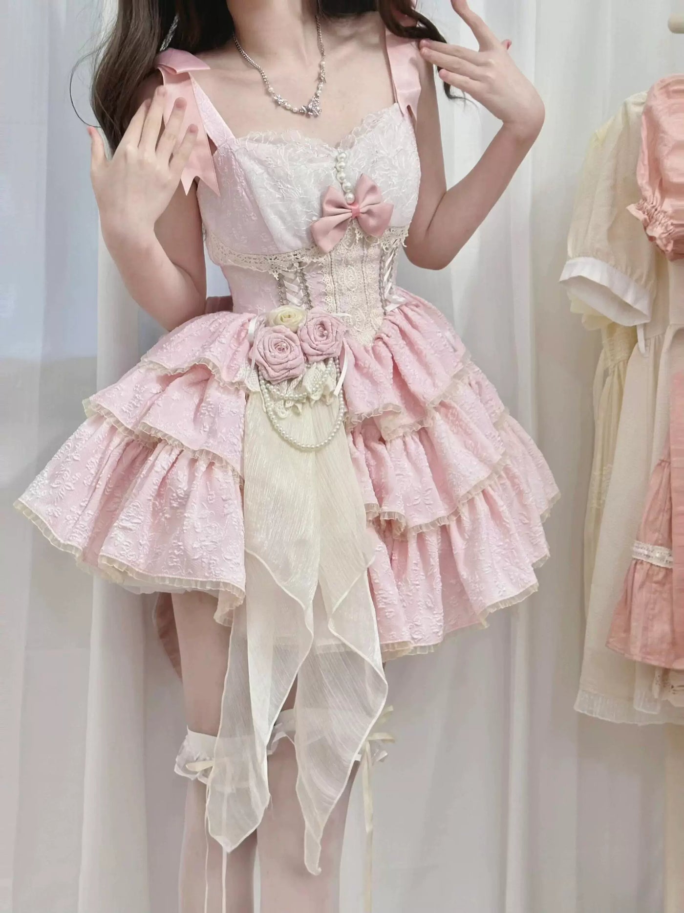 Pink JSK with cream lace bodice, layered ruffles, rose waist accessory, and long front drape.