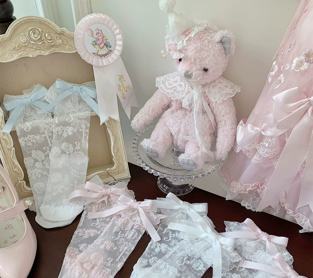 Rose-pattern socks with pastel ribbon bows and lace cuffs displayed in a styled still life.