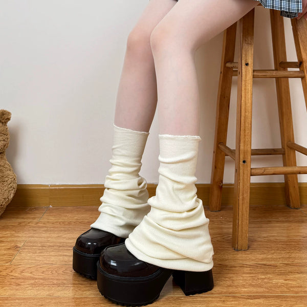 White ribbed slouch leg warmers styled with a navy plaid skirt and black platform loafers.
