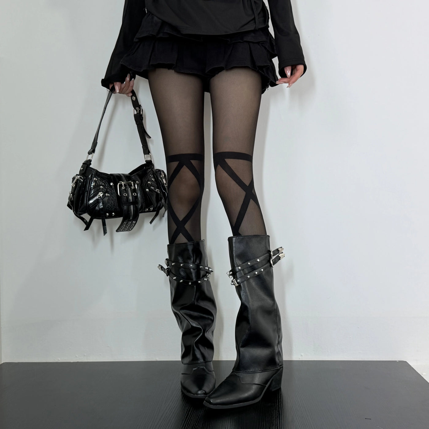 Black crisscross stockings styled with black boots and a short ruffled skirt.