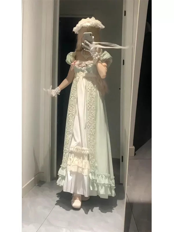 Pale green empire-style dress with puff sleeves, decorative front panels and a ruffled hem shown in a mirror.