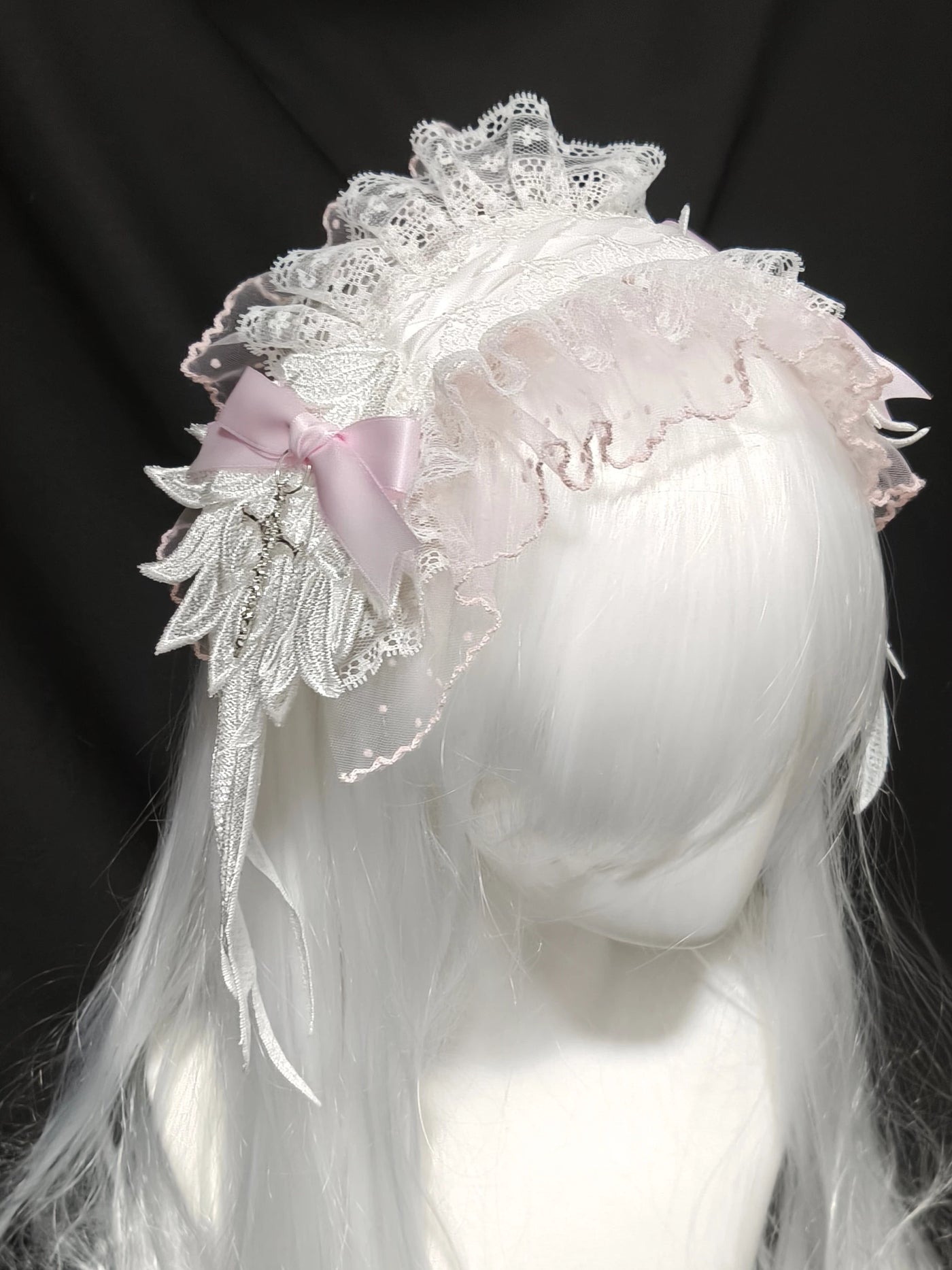 White lace angel hairband with a pink bow and hanging trim on a pale wig.