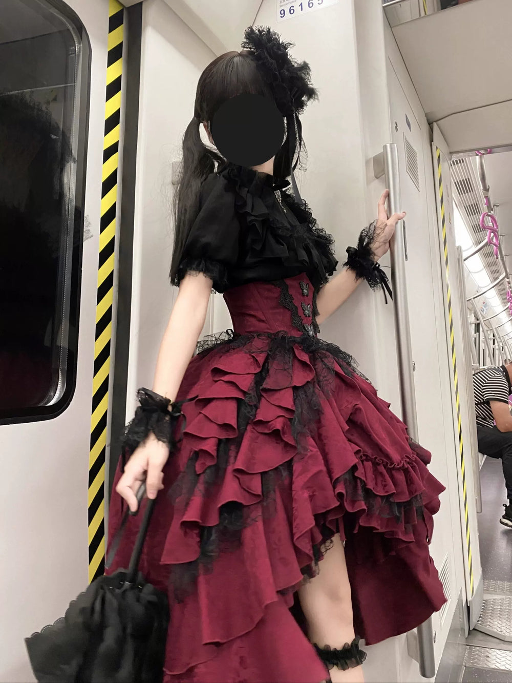 Black blouse and red ruffled suspender skirt set worn in a train carriage.