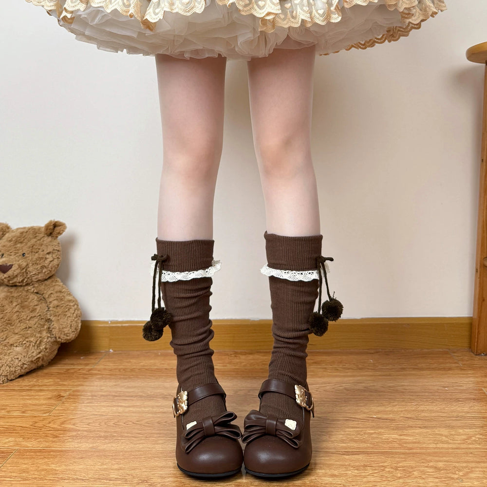 Brown and white cuffed calf socks with bow-tied pom-poms and Mary Jane shoes.