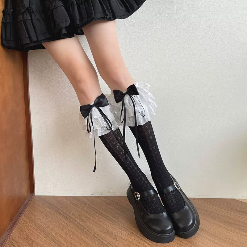 White mid-calf Lolita socks with layered lace cuffs, oversized bows, and an openwork heart pattern.