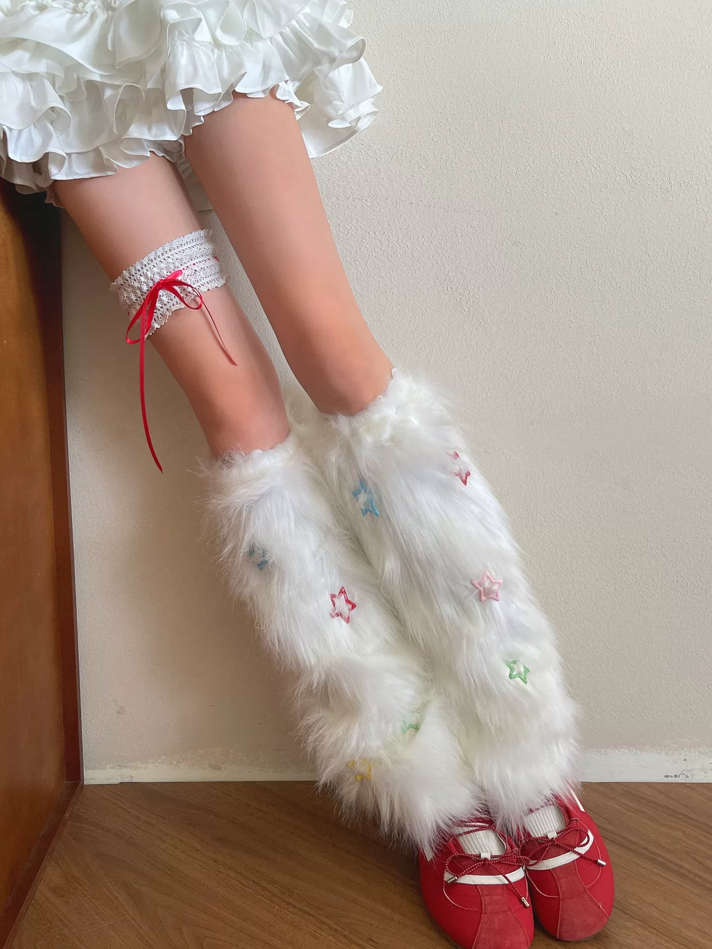 White long-pile sock covers with multicolor star motifs and a separate white garter with red ribbon.