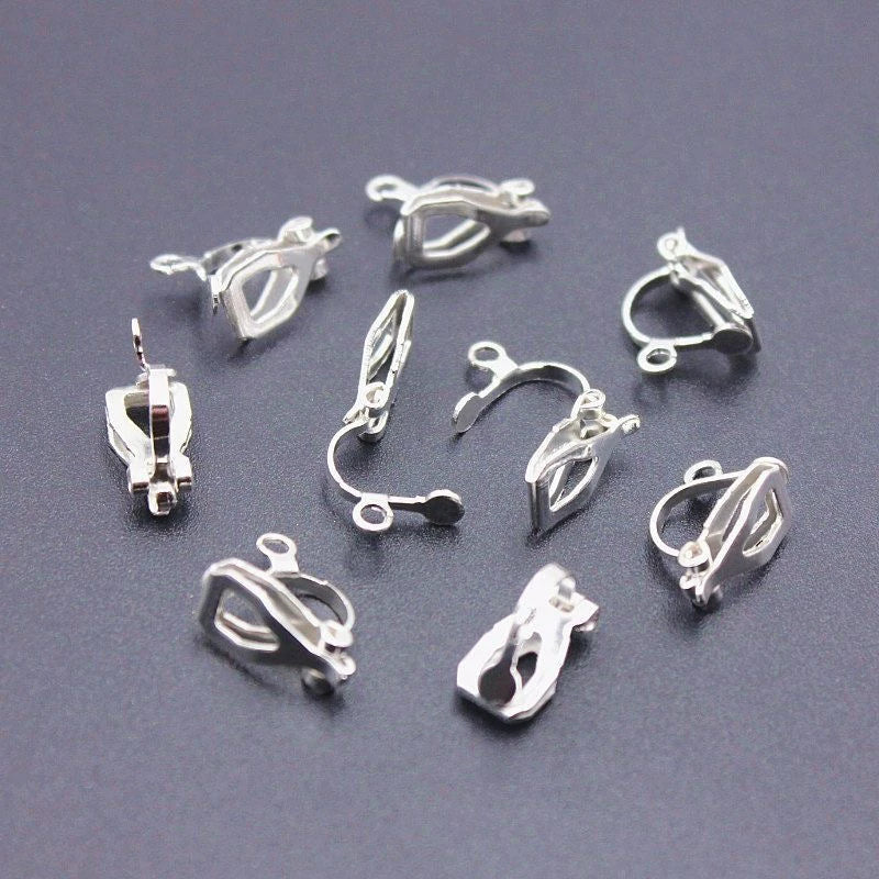 Silver-tone bow and charm earrings displayed on ceramic plates.