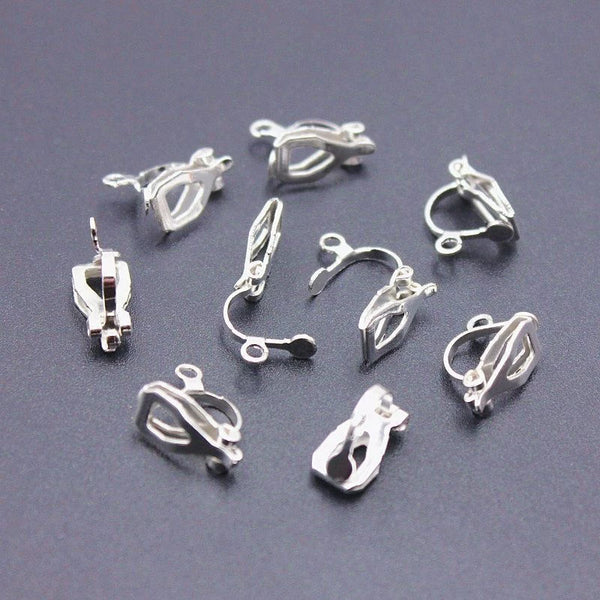 Silver-tone bow and charm earrings displayed on ceramic plates.
