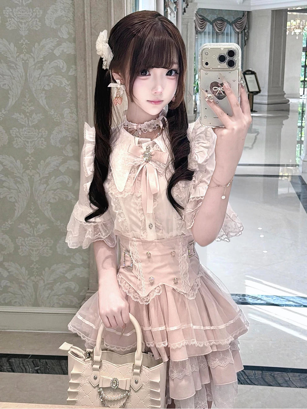 Modelled view of a white-and-pink lace-trimmed top and layered skirt set with bow accents.