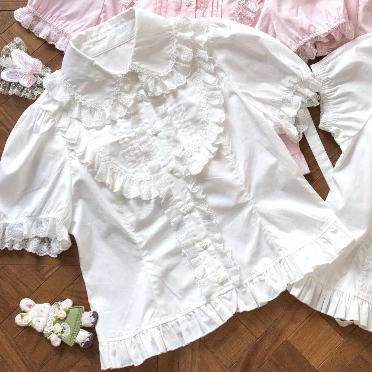 White ruffle blouse laid flat with a lace-trimmed collar and puff sleeves.