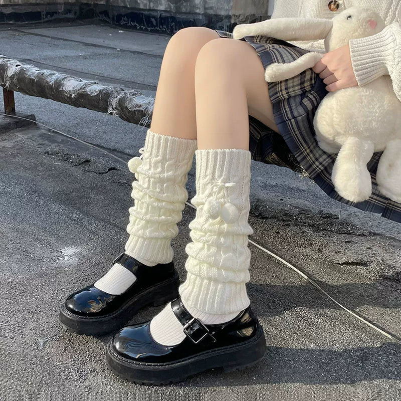 Milky white cable-knit pom-pom sock covers worn scrunched over black Mary Jane shoes.