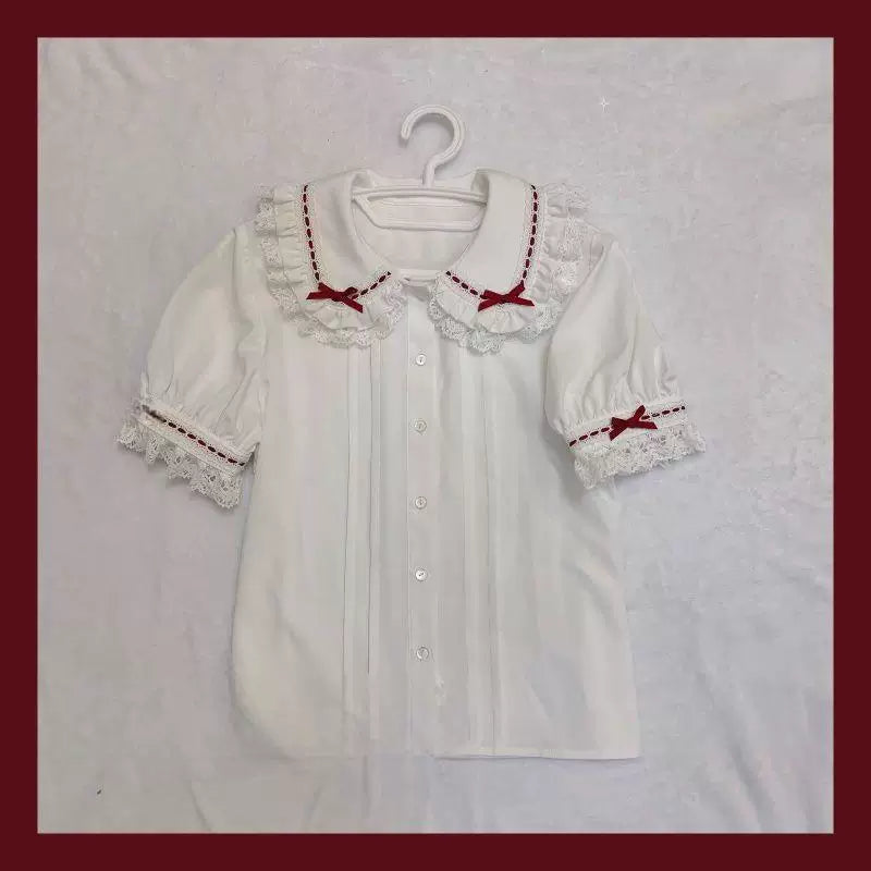 White short-sleeve blouse with a layered lace doll collar and red bow accents.
