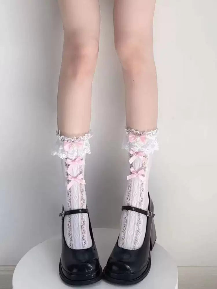 White lace-trimmed mid-calf socks with pink bows styled beneath a pale ruffled skirt.