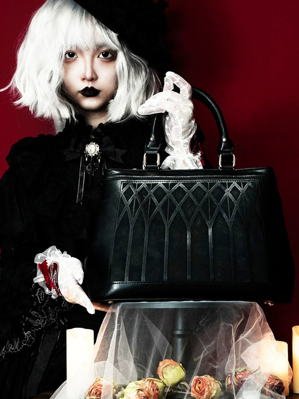Black Gothic tote bag with pointed World Tree paneling held before a deep red background.