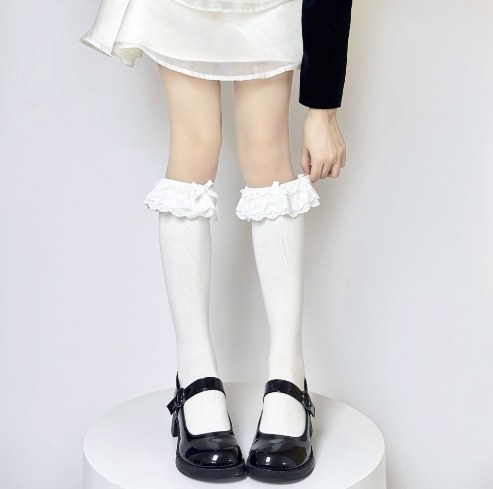 White ruffled lace mid-calf socks worn with black Mary Jane shoes.