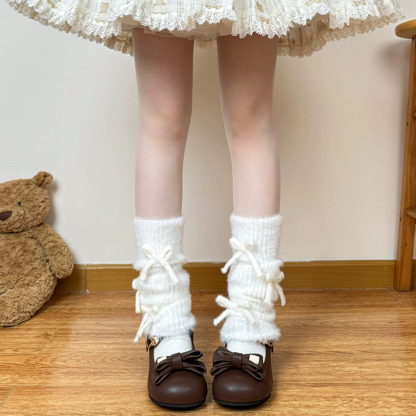 White plush leg warmers with stacked ruffles and tie bows styled with Mary Jane shoes