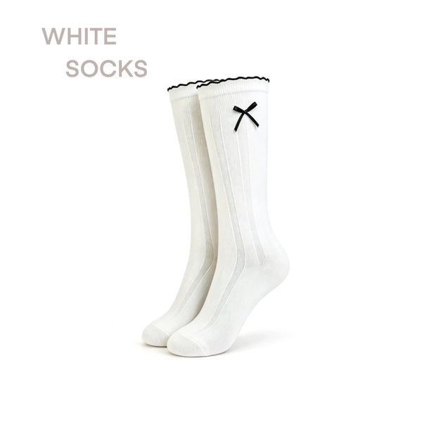 White mid-calf socks with black three-stripe cuffs styled with black bow shoes.
