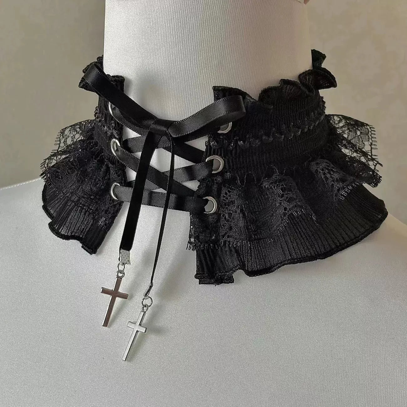Black lace neckwear with criss-cross straps and dangling cross charms.