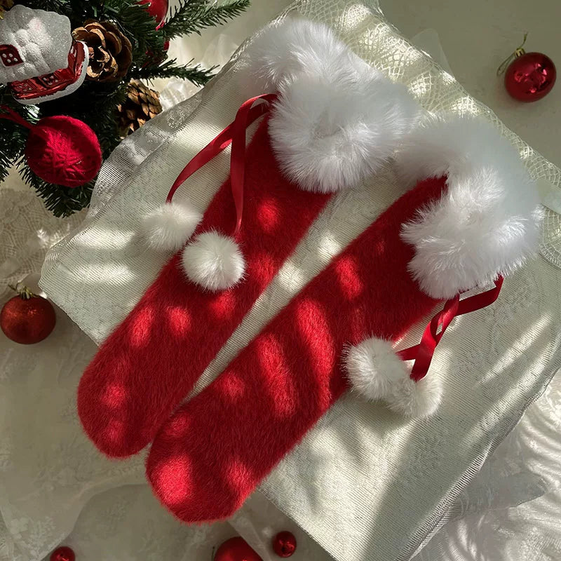 White scrunched socks with fluffy cuffs and festive red ribbon accents beside black platform shoes.