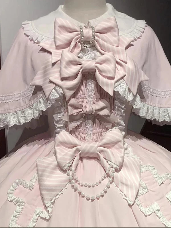 Creamy pink JSK dress with layered ruffles, bows and matching cape on a mannequin