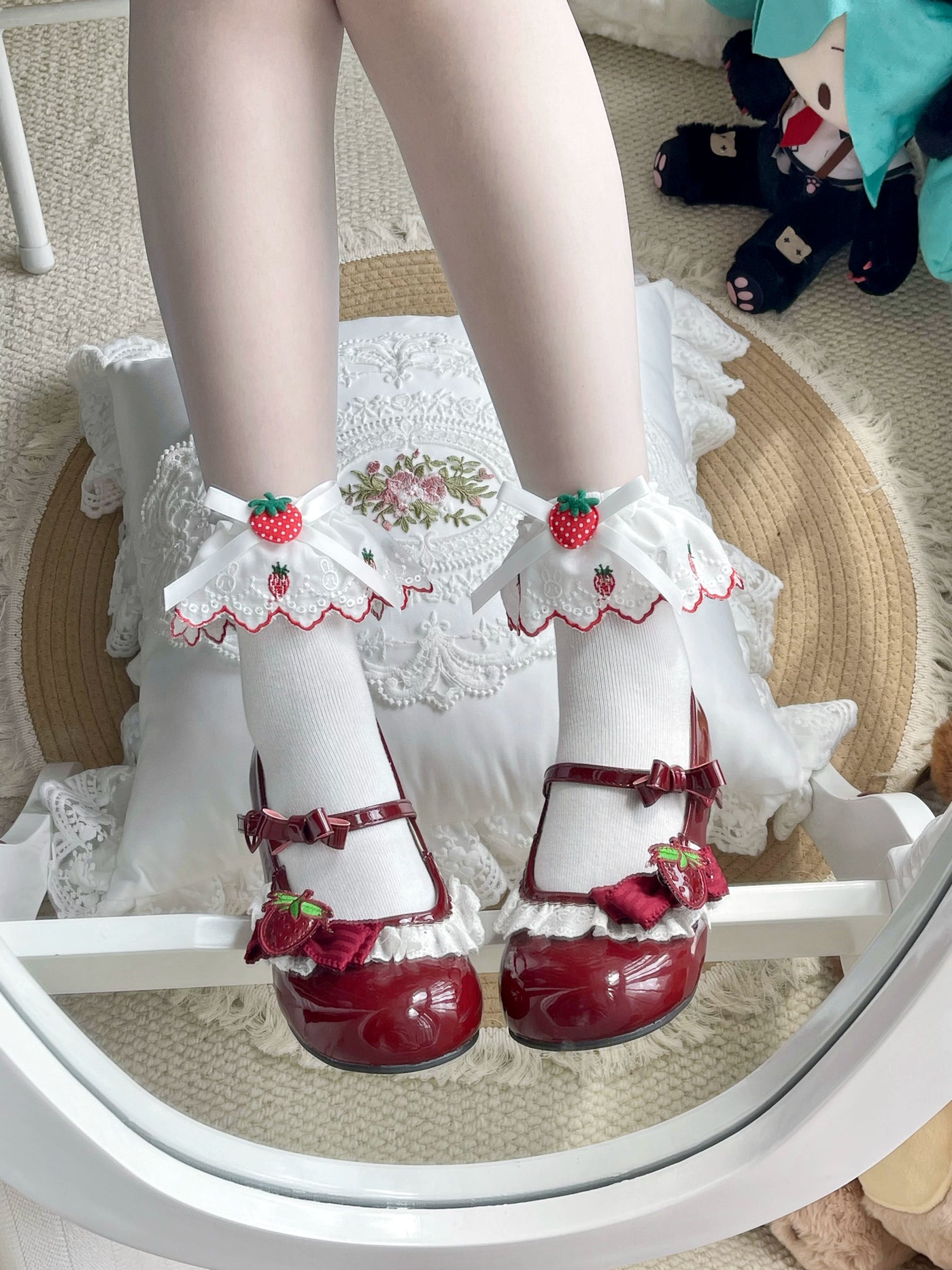 White mid-calf socks with strawberry motifs, bows, and lace cuffs styled with glossy red shoes.
