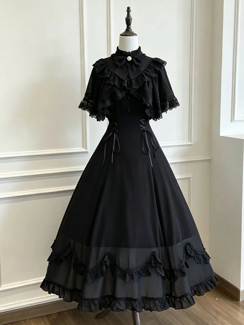 Black OP dress displayed on a mannequin with a ruffled collar, layered lace trim and long skirt.