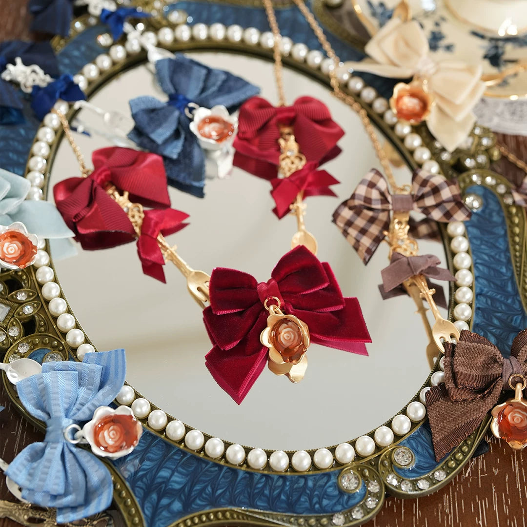 Star Box Drink Me! wine-red necklace with a bow and flower pendant displayed on a mirror.