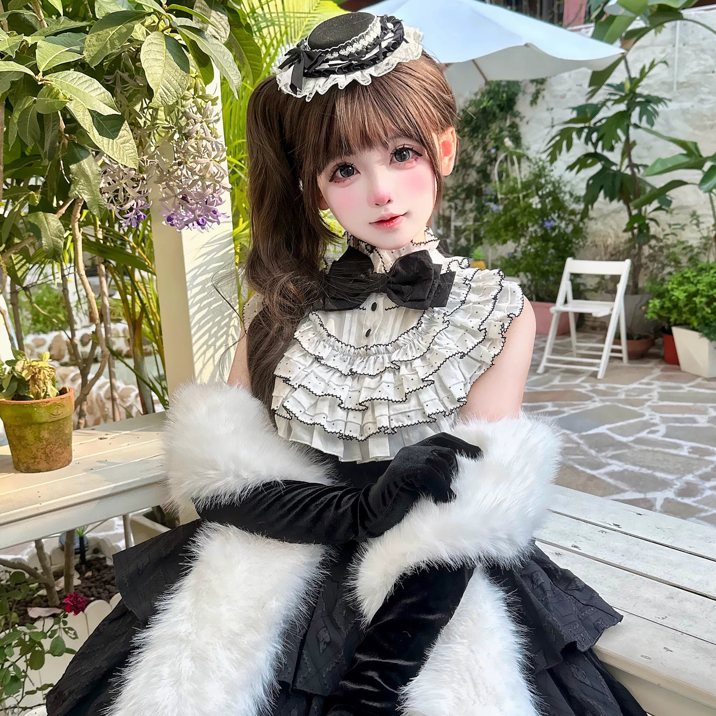 Model wearing a black one-piece dress with a white ruffle collar and layered full skirt.