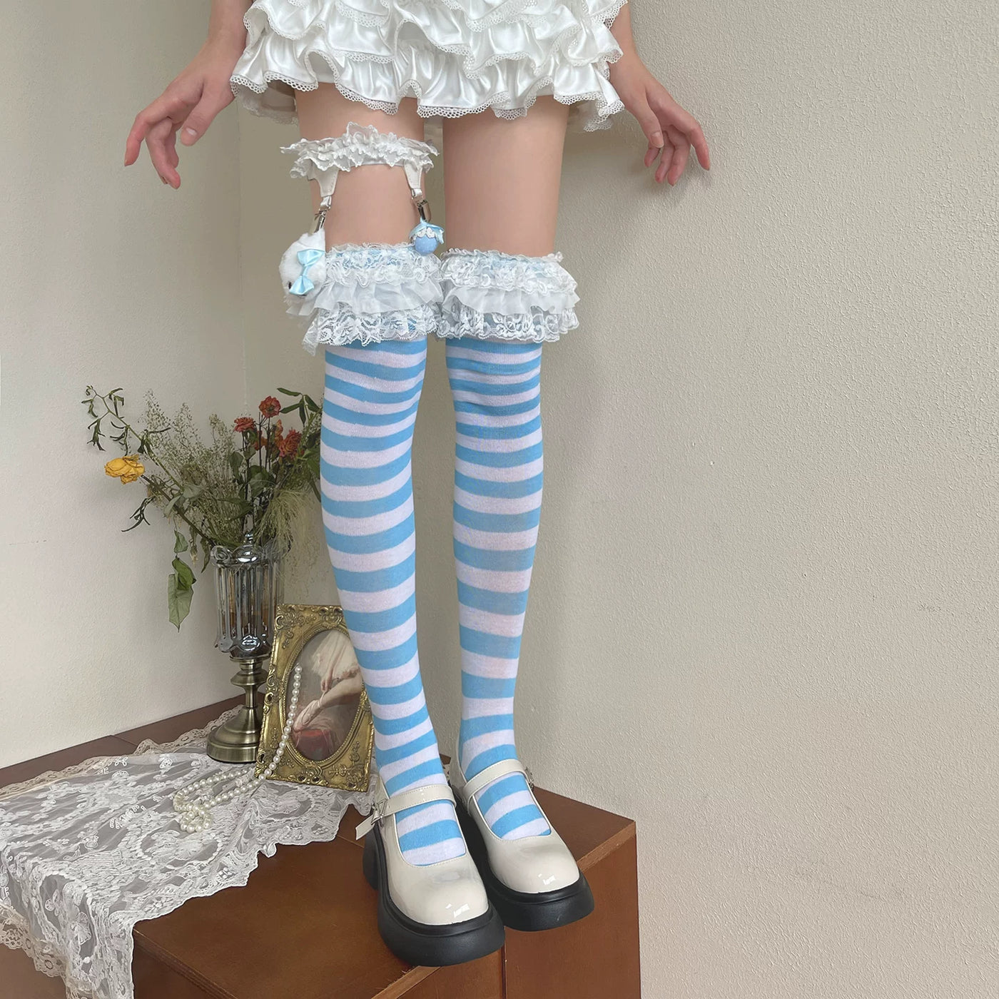 Blue-and-white striped over-the-knee socks with lace garters and white shoes