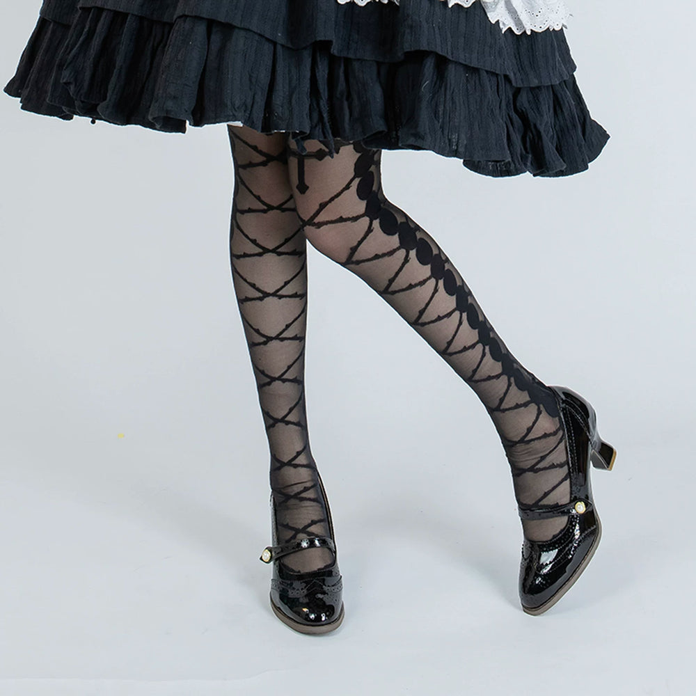 Black and white sheer hosiery with a crossed-thorn pattern styled under a layered skirt.