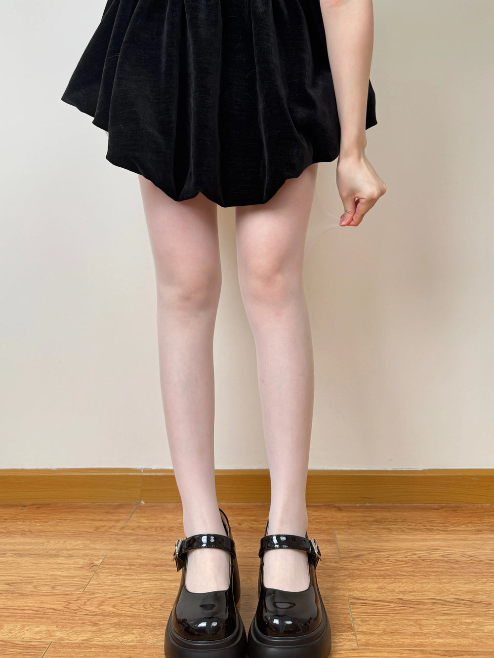 Milky-yellow ultra-thin pantyhose shown beneath a black dress.