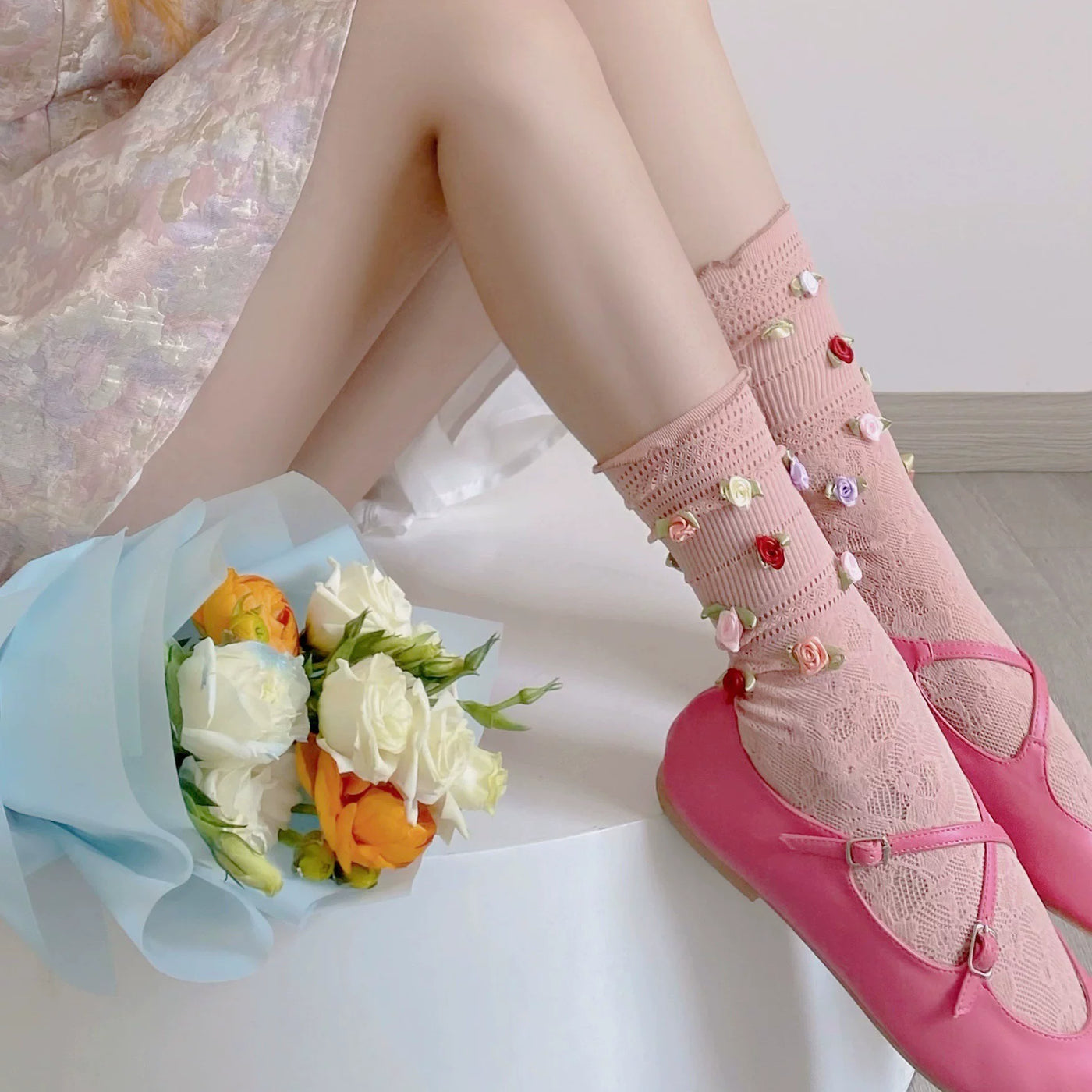Pink floral lace mid-calf socks with rose accents styled with pink Mary Jane shoes.
