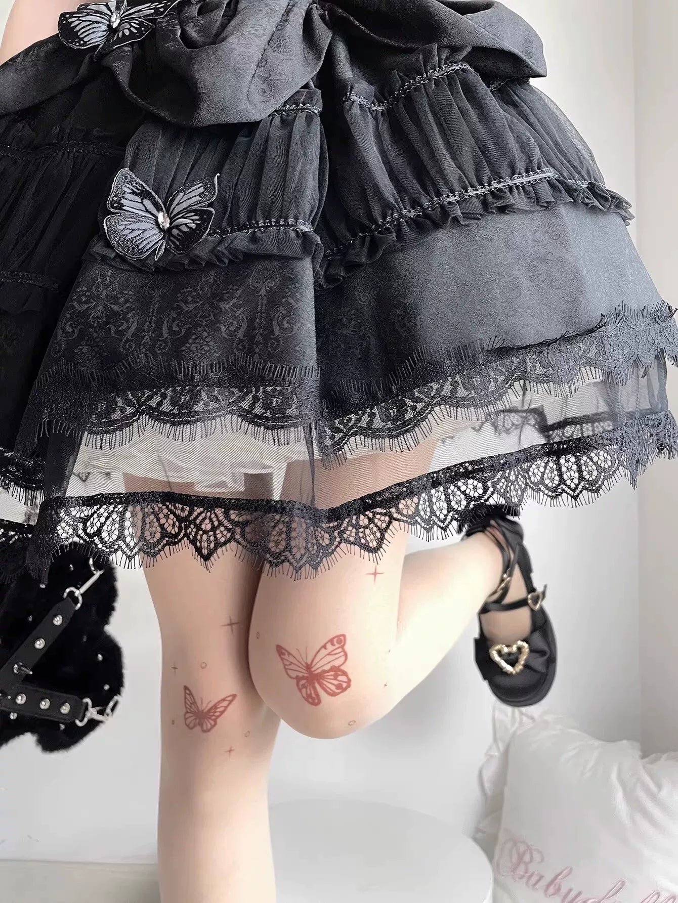 Skin-tone pantyhose with butterfly motifs beneath a black ruffled skirt