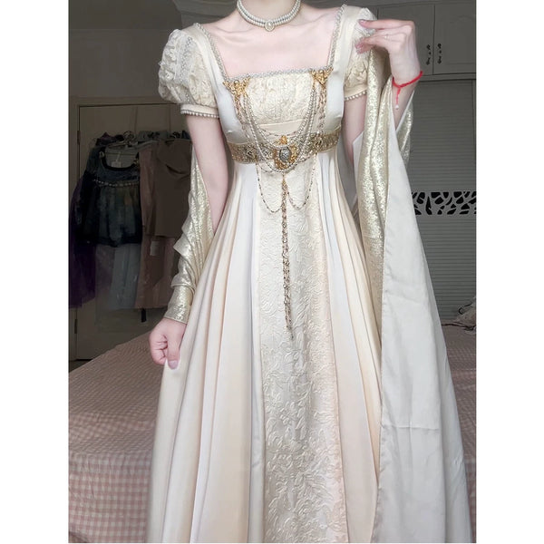 Model wearing an ivory empire-waist dress with embossed floral texture, puff sleeves and a matching shawl.