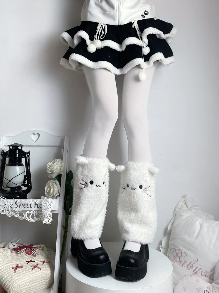 White plush cat-face leg warmers with ears and whisker details over black platform shoes.