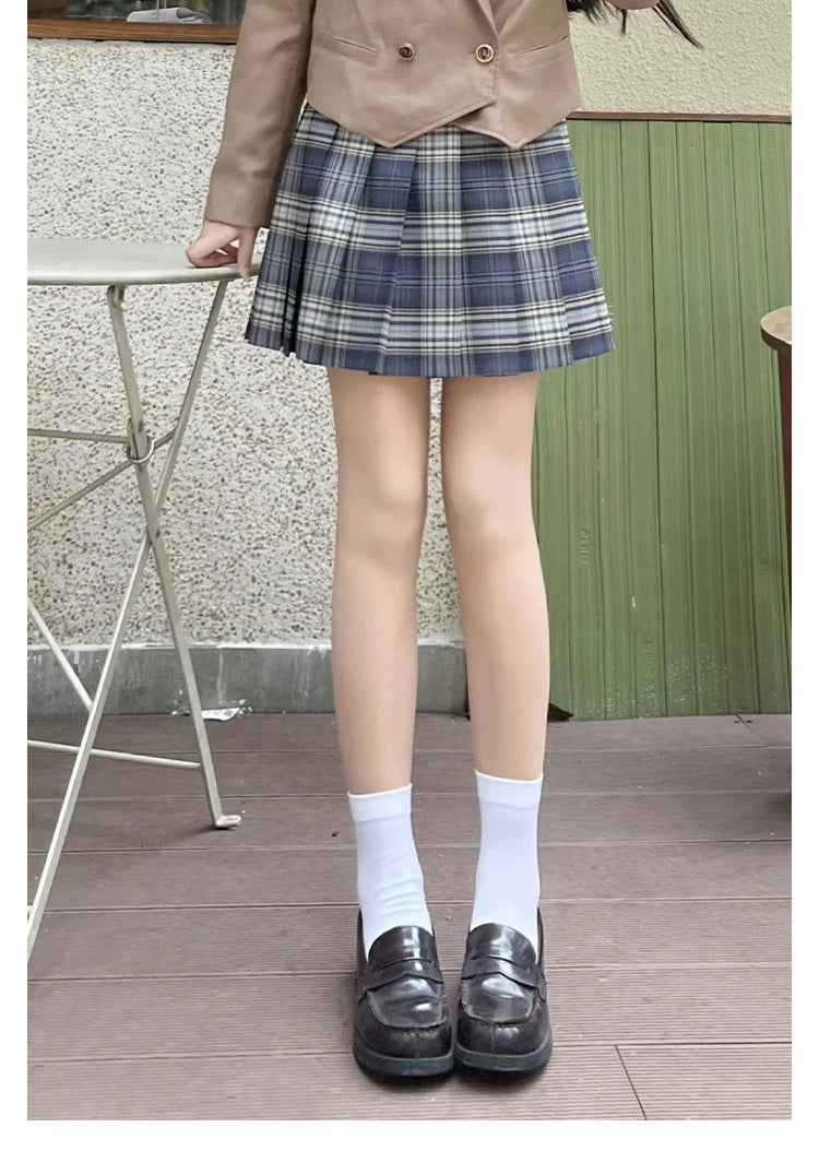 Model wearing skin-tone footed tights with a blue plaid skirt and black loafers