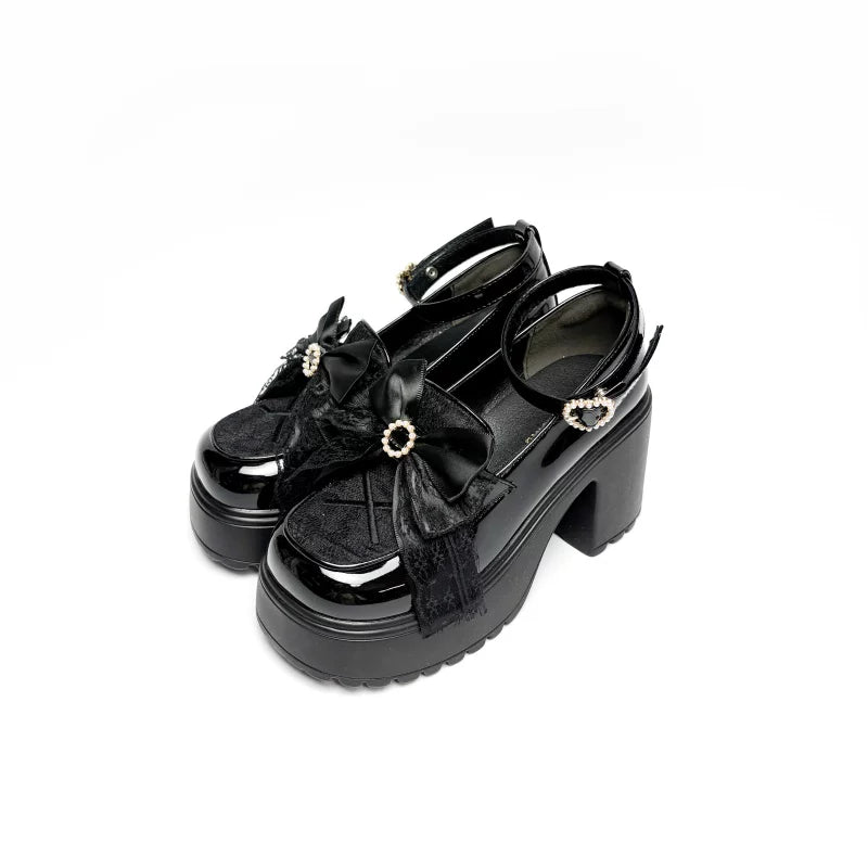 Black glossy Lolita platform heels with bows, lace trim, and heart-shaped side accents.
