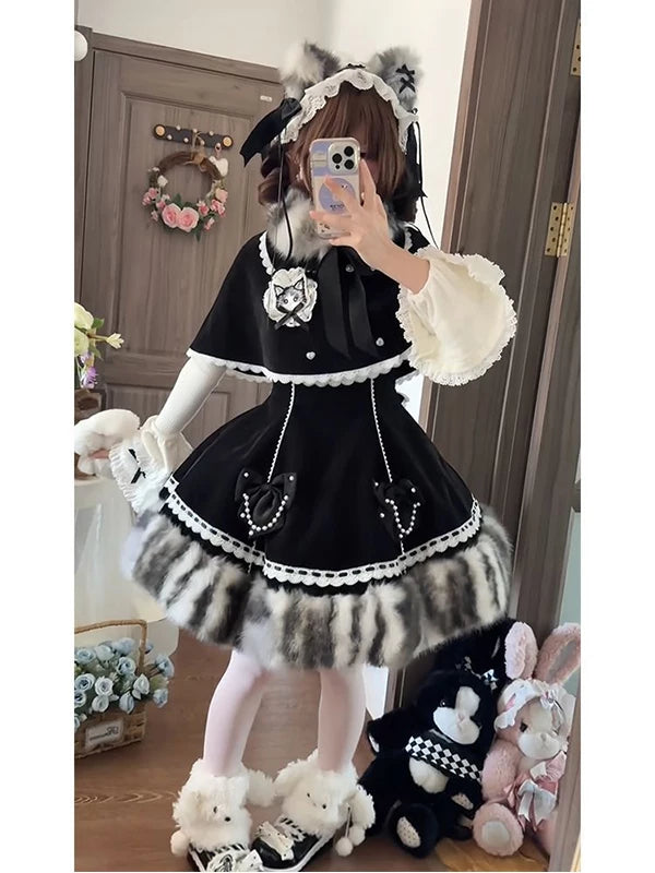 Black cape-and-dress coordinate with white lace trim and bow details shown on a model.