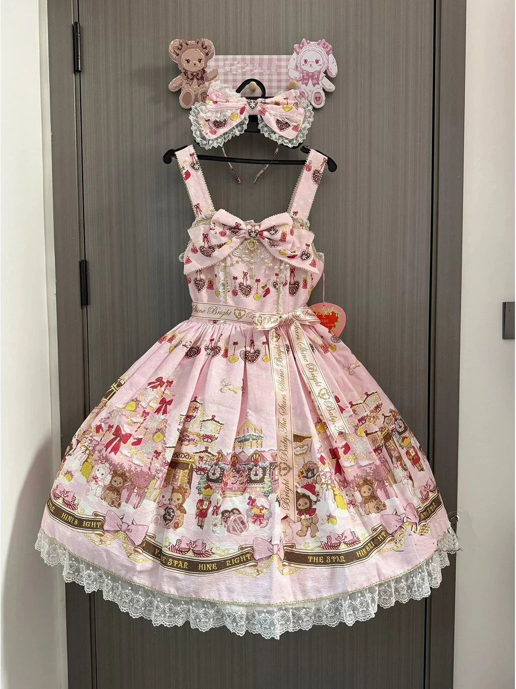 Pink rabbit-and-bear JSK dress with bows and lace trim displayed on a hanger.