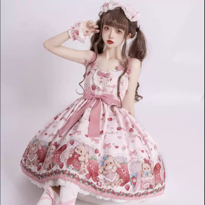 Pink rabbit-and-strawberry JSK dress shown on a model with a wide waist bow and illustrated hem.