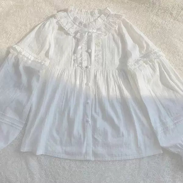 White long-sleeve blouse with a ruffled collar, lace trim and button front shown in close-up.