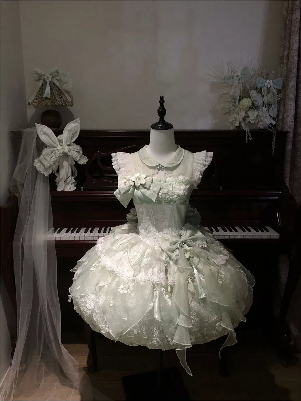 Creamy pale green bud-shaped JSK dress with rounded collar and floral chest detail on a mannequin