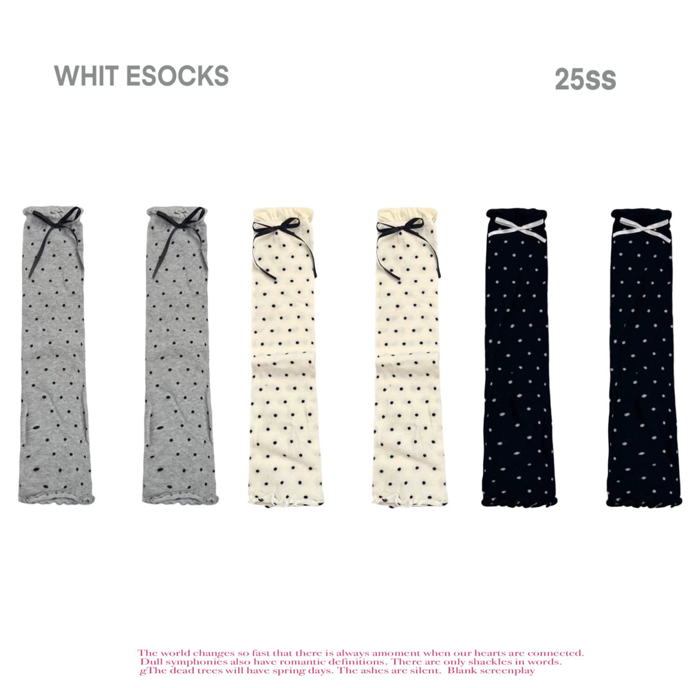 Cream ribbed knit socks with black polka dots, white floral lace cuff, and black satin bow accents