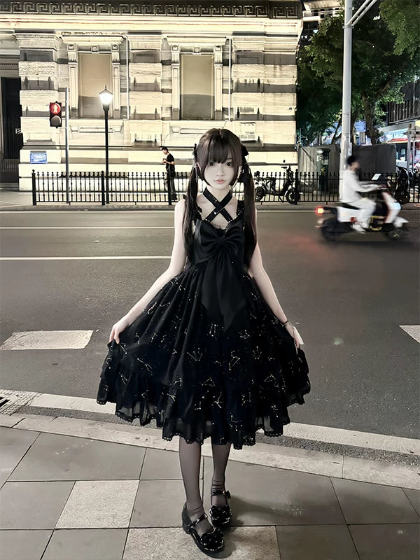Creamy black one-piece dress with a tiered skirt and gold-foil detailing, shown on a model.