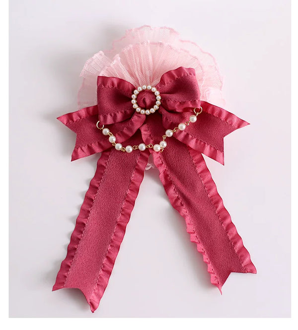 Magenta lace accessory with layered ruffles, a large bow and pearl chain on a plain background.